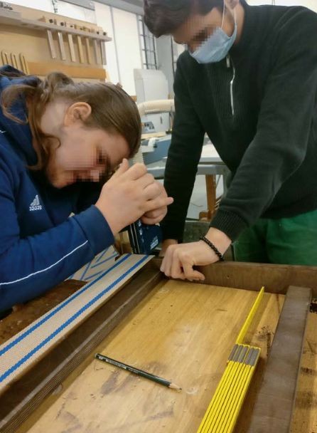 Zwei Jugendliche (Gesichter verpixelt) arbeiten mit dem Schraubenzieher an einem Werkstück